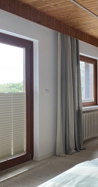 Foto eines Schlafzimmers mit Plissees und Vorhänge als Sonnen- und Sicht Schutz
