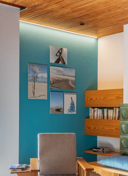 Foto einer Wand, an der eine Galerie mit Bildern von verschiedenen Ausflugszielen hängt. Die Fotos werden von einem LED-Leistenprofil angestrahlt, das für eine stimmungsvolle Beleuchtung sorgt.
