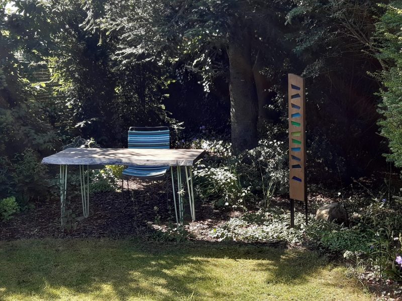 Foto der Gartenecke mit Stele im Schatten