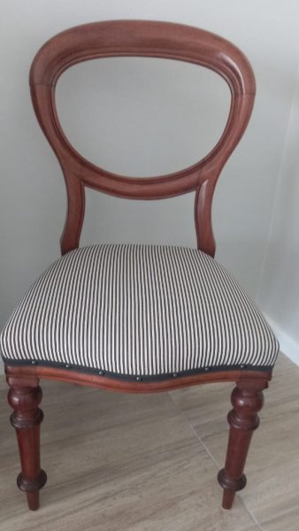 A well loved antique chair upholstered in ticking fabric always useful as extra seating.