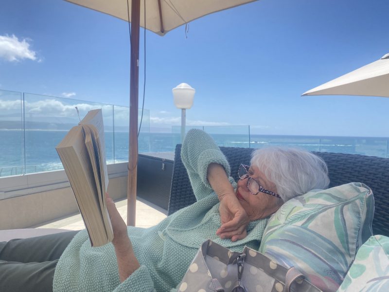 Photo of a person reading a book with the Indian Ocean in the background South Africa | Copper Beech Place Homestory