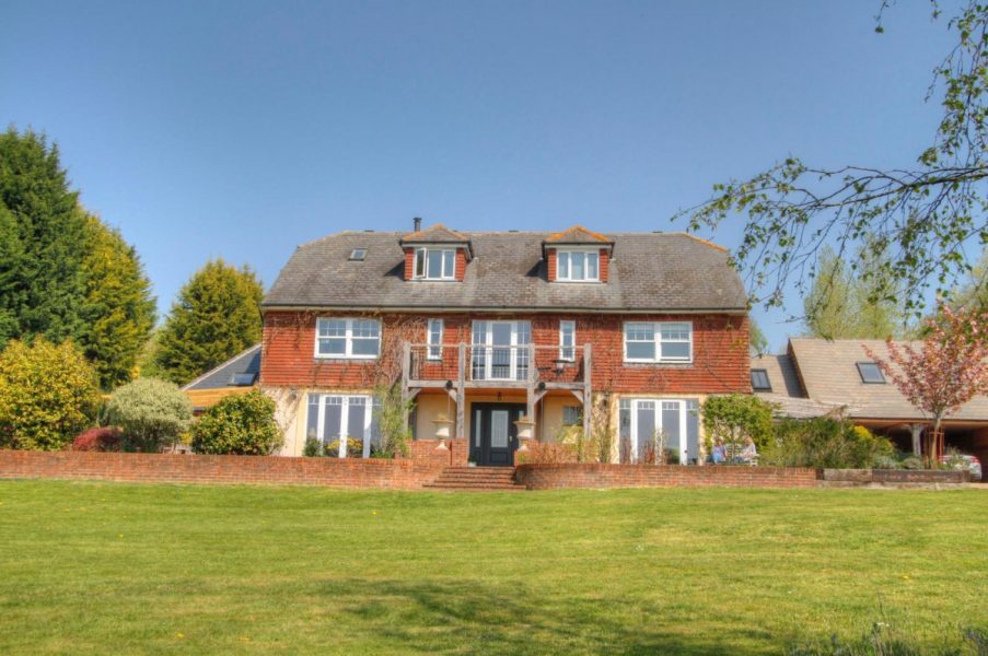 Photo of the front facade showing the extended window space for more light and the face brick retaining wall and steps that were built to lead down into the garden