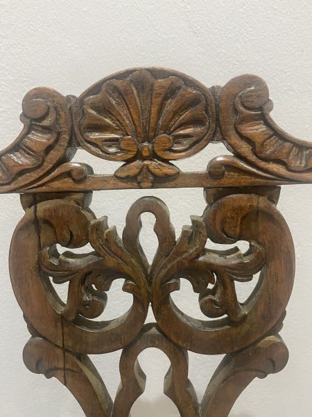 Photo of the ornately carved backrest of an antique chair