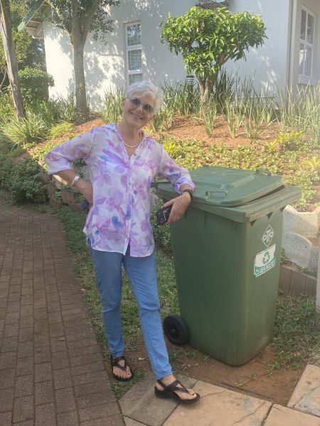 Photo of a woman next to a green rubbish bin